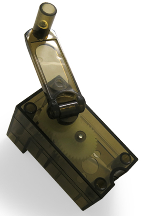 A close-up image of the E-Blox Hand Crank - E-Blox® (requires generator part 99), a small, transparent plastic gearbox with visible gears inside, perfect for a Circuit Builder. The gearbox features a rectangular base and an extended arm or lever on top that resembles a hand crank. The plastic is tinted a smoky gray color.