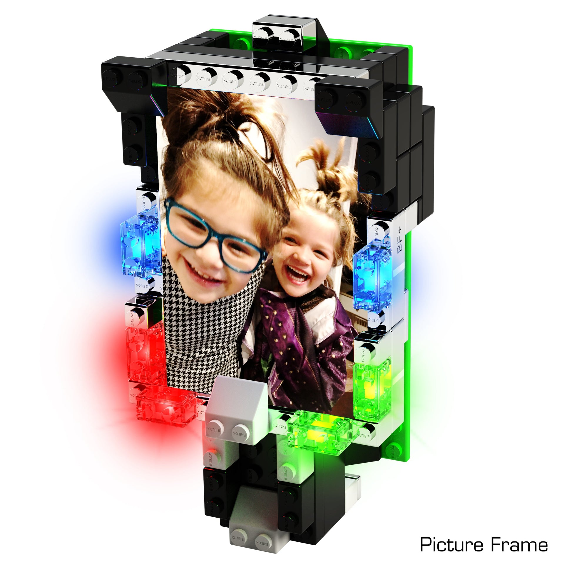 A photo frame created with colorful pieces from the Power Blox™ Builds Plus Set - E-Blox® - LED Light-Up Building Blocks Student Set showcases a picture of two smiling children. The children, both wearing glasses and polka-dot clothing, are embracing and looking into the camera. The frame is adorned with multicolored lights and components from E-Blox, making it perfect for fostering creativity in STEM education.