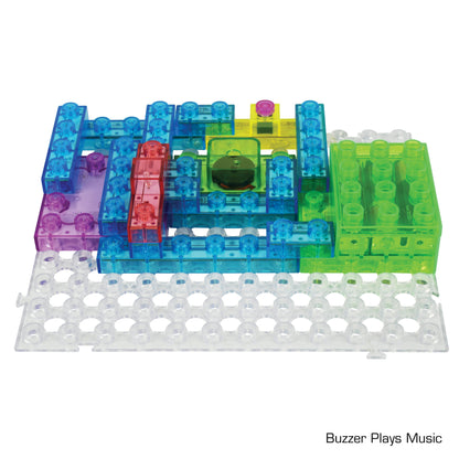 A vibrant Circuit Blox™ 800 Classroom Set - E-Blox® Circuit Board Building Blocks Toys for Kids features a colorful array of snap circuit components on a white perforated board. The arrangement includes pieces in blue, green, purple, and transparent shades, along with a distinctive black circular buzzer. Text at the bottom right corner reads "Buzzer Plays Music." This engaging kit complements any STEM curriculum.