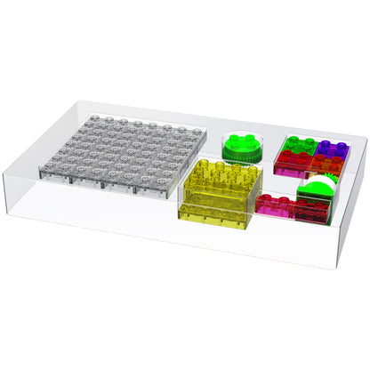 The Circuit Blox™ Lights 'n Motion - Student Set by E-Blox is a transparent rectangular case containing vibrant, Lego-like building blocks designed for educational play. The set includes a large grey flat piece, a red piece, a yellow piece, two round pieces (one green and one split between green and white), and a small green piece. It's an ideal STEM kit.