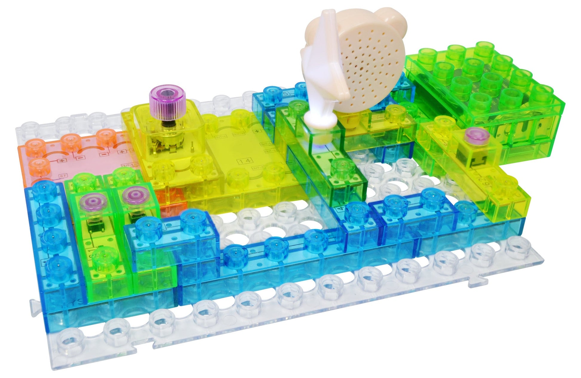 The image displays the E-Blox Circuit Blox™ 120 Project Classroom Set, featuring colorful translucent plastic blocks in blue, green, and yellow. These blocks are arranged in a grid pattern and include electronic components like a speaker and buttons. Ideal for any STEM program, the setup allows for pathways of electricity to be formed by connecting the blocks.