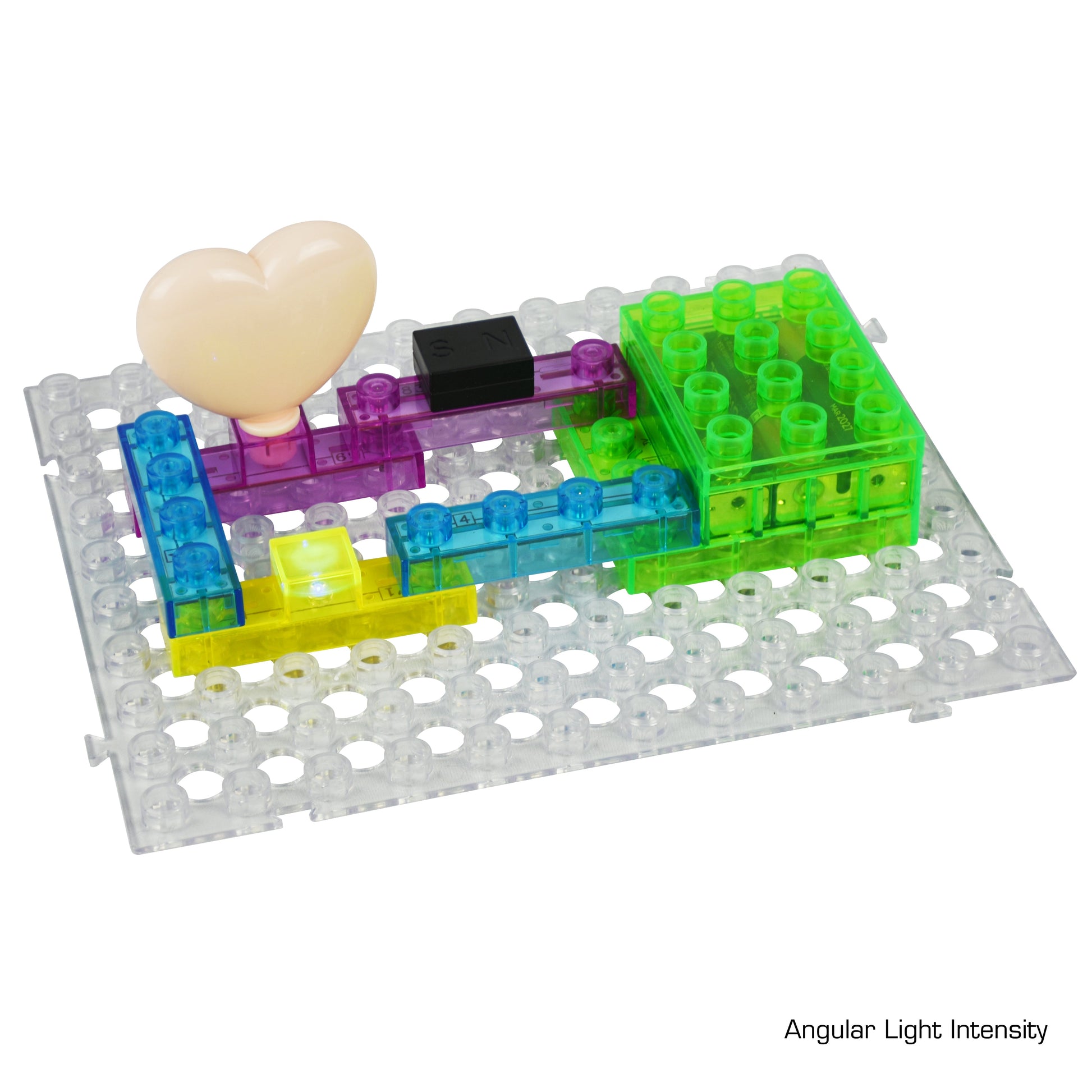 A clear base grid from the Circuit Blox™ 59 project Classroom Set – E-Blox® Circuit Board Building Blocks Educational Sets holds various translucent, colorful blocks arranged in a pattern. The blocks are green, blue, yellow, and purple, and there is a pink heart-shaped object placed on the grid. The image is labeled "Angular Light Intensity" in the bottom-right corner, aligning with NGSS requirements for STEM education.