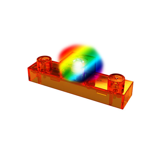 A transparent orange rectangular LEGO brick with two round studs on top sits against a white background. Resting atop the brick is a smaller E-Blox Circuit Blox™ - Colorful LED piece emitting a bright, colorful light display.