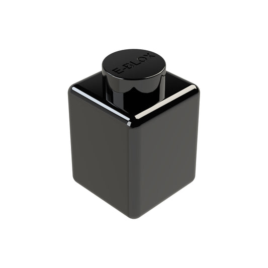 A sleek, black E-Blox 1x1 Block ink bottle features a cube shape with a round cap indented with the brand's logo. This modern design has a reflective surface and is available in seven different colors.