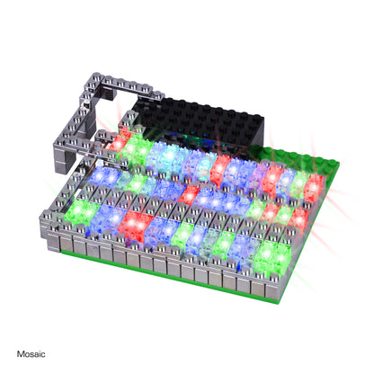 The Power Blox Flashing Frenzy by E-Blox features an array of colorful, illuminated bricks arranged in red, green, and blue sections. The design includes raised gray structures around the edges and a raised black section at the top, highlighting its integration with STEM curriculum principles.