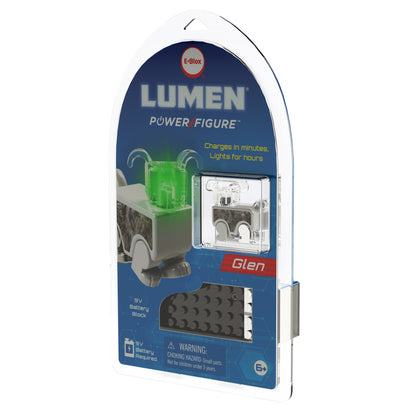 The packaging of the LUMEN®- Glen Illuminated Mini Figure from E-Blox, Inc. features a figure in the shape of a small vehicle with a glowing green light. The package includes a 9-volt battery block and a black connector piece, and it is suitable for ages 6 and up with a warning about small parts. This product is part of the exciting Story Blox™ series.