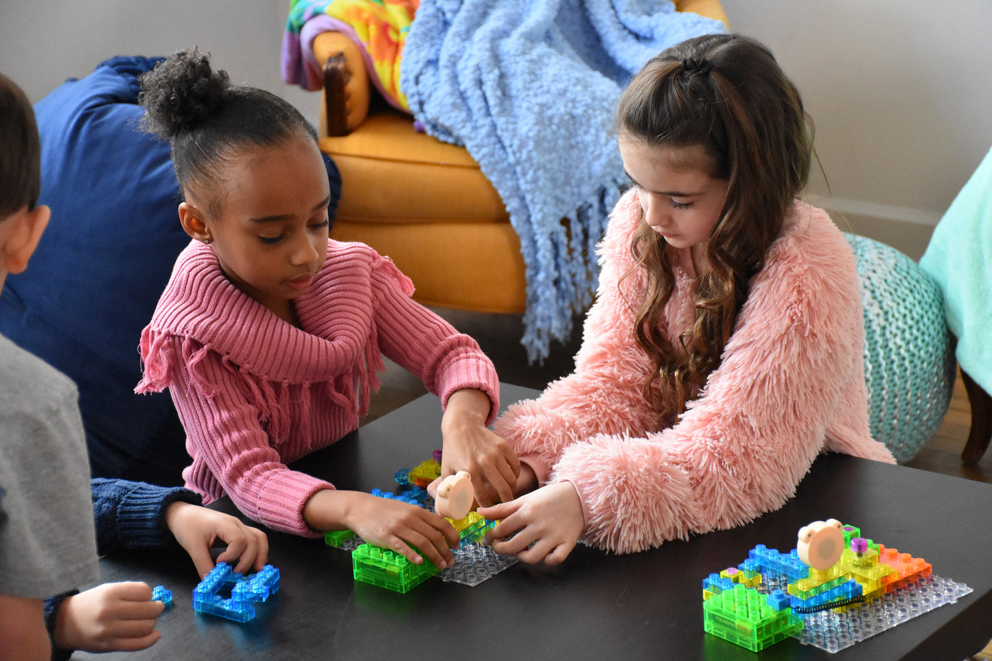 2 girls build a circuit on a table with another circuit built in front