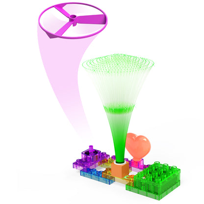 The Circuit Blox™ 4 Project Student Set from E-Blox features a transparent, multicolored electronic kit with various interconnected components. It includes a purple propeller, a green fiber-optic-like structure, and a pink heart-shaped balloon, creating an intricate and colorful assembly perfect for educational play.